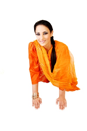 A very pretty east indian teenage girl lying on the floor in her traditional indian dress and long black hair in a ponytail for white background の写真素材