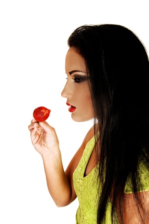 A close up shoot on a gorgeous teen girl with long black hair eating a bigstrawberry for white background の写真素材