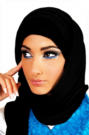 A pretty and young teen girl with a black headscarf and nice makeuplooking into the camera with one finger on her face for white background の写真素材
