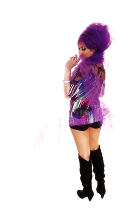A young tall woman standing for white background in black shortsand long boots with lilac twill around her head の写真素材