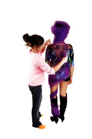 A woman model standing from the back for white background get somehelp from the makeup artist with her outfit の写真素材