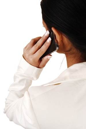 A young business woman standing from the back in a white suit talking on her cell phone for white background の写真素材