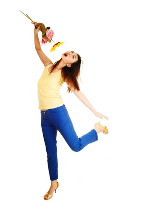 A very tall young Chinese woman dancing for white background in bluedress pants and yellow top, with flowers in her hand の写真素材