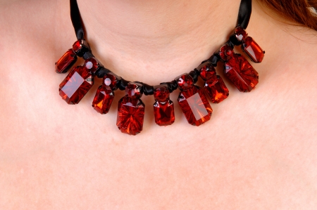 A closeup picture of a beautiful burgundy necklace around the neck of awoman の写真素材