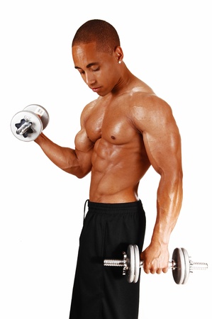 A picture from the side of a young bodybuilder in black shorts liftingtwo silver colour dumbbells in his exercises の写真素材