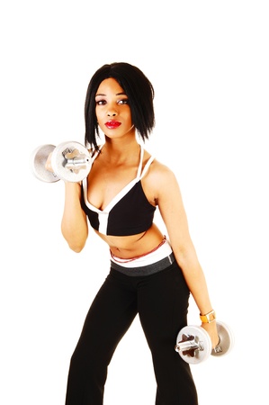 A slim young woman in black exercise clothing working out with silvercolor dumbbells for white background の写真素材