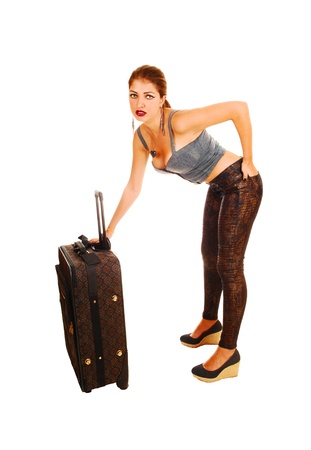 A young pretty woman in tights standing for white background with asuitcase looks worried の写真素材
