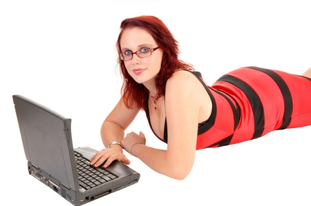 A red hair teen girl lying on the floor with glasses and working on herlaptop for white background の写真素材