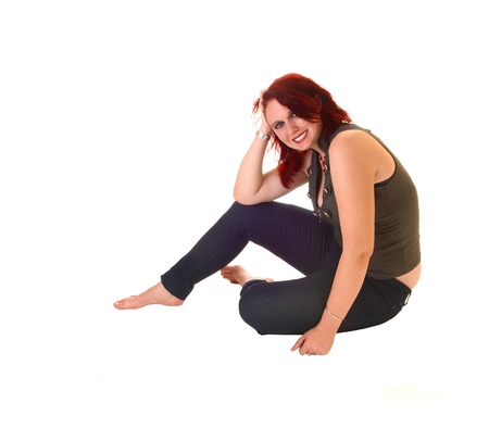 Lovely young teen girl in jeans and a olive green top sitting bare feet onthe floor, smiling for white background の写真素材