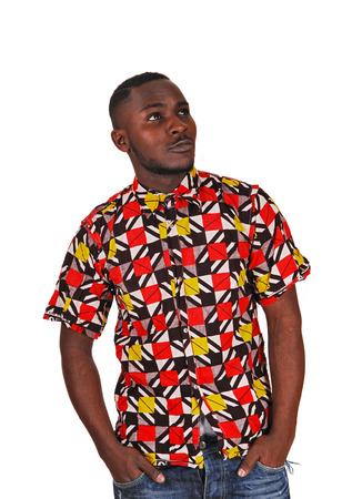 A handsome young black man in a colorful shirt and his hands in hispocket, looking up for white background の写真素材