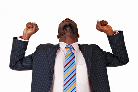 A very happy black business man raising his arms and his head backfor white background の写真素材