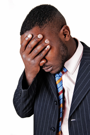 A closeup picture of a black man in a suit, holding his hand on his facefor sadness, for white background の写真素材