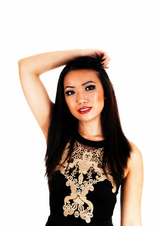 A slim young Chinese woman standing in a black dress and longblack hair for white background の写真素材