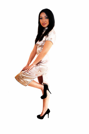 A beautiful young Chinese woman in a long silver dress and long black hairstanding for white background の写真素材