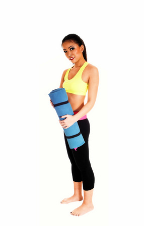 A full body picture of a slim Chinese woman in exercise clothing standingbare feet for white background holding a yoga matt の写真素材