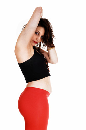 A closeup picture of a pretty woman in a black top and red tights standing in profile, isolated for white background の写真素材
