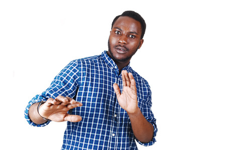 A scared looking young black man in a blue shirt with his armの写真素材