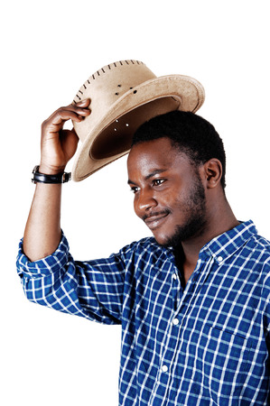 A handsome black man in a blue shirt lifting his cowboy hat and smilingisolated for white background の写真素材