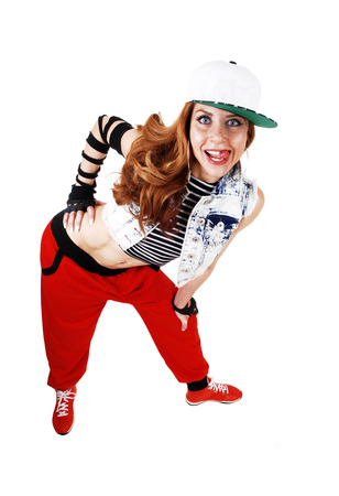 A lovely woman in red pants, jeans jacket and a hat standing bendforwards isolated on white background の写真素材
