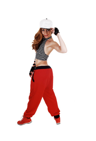 A lovely woman in red pants, jeans jacket and a hat standing from theback, isolated on white background の写真素材