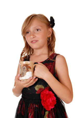 A blond young girl holding a cup in a nice black dress, isolated forwhite background.の写真素材