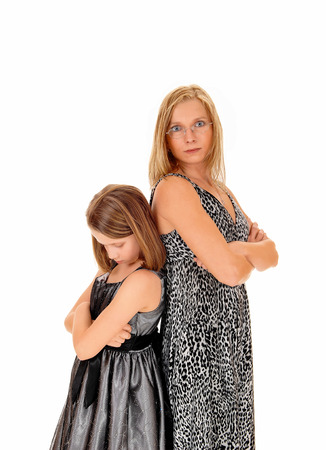 A mother and daughter standing back to back, isolated for whitebackground, being mad to each other.の写真素材