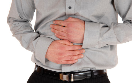A closeup picture of the stomach of a young man holding his hands onthe stomach for heavy pain, isolated for white background.の写真素材