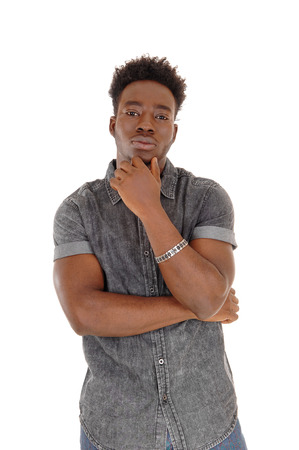A portrait of a young African American man with one hand on his chin,
standing for white background and thinking.の写真素材