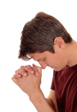 A young man with folded hands praying in closeup, isolated for
white background.の写真素材