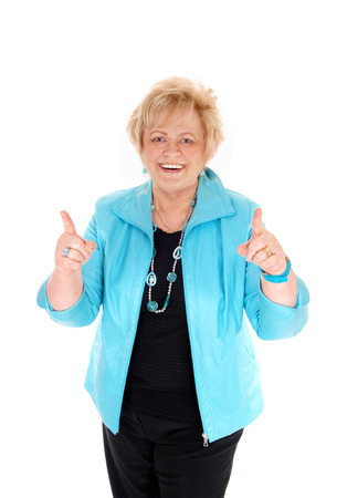 A smiling happy middle age woman in a blue jacket pointing up with
her finger, isolated for white background.の写真素材