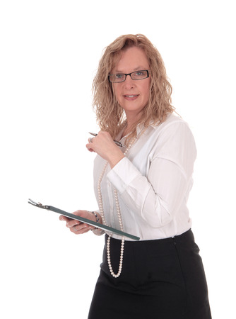 A business woman standing in a black skirt white blouse holding
her clipboard, looking into the camera, isolated for white background.の写真素材