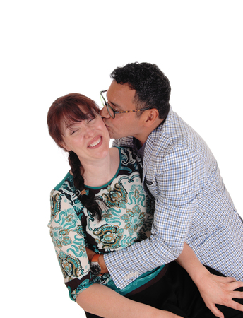 A Hispanic man embracing his wife with a big kiss, she is laughing,
isolated for white background.の写真素材