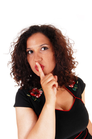 A lovely young woman with curly brunette hair in closeup holding one
finger over her mouth, isolated for white background.の写真素材