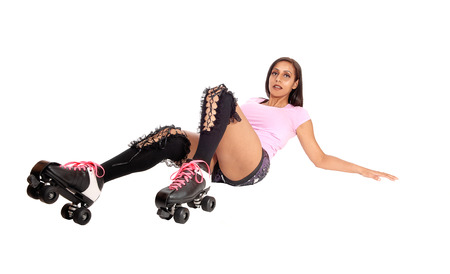A pretty woman with roller skates and shorts lying on the floor
after falling on her butt, isolated for white backgroundの写真素材