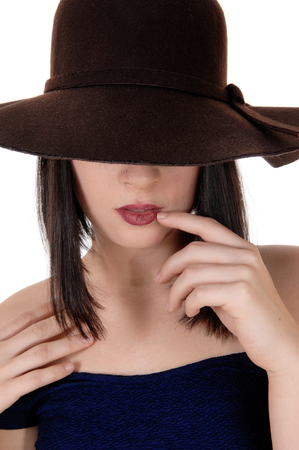 A closeup image of the head of a beautiful woman with a brown hat
over her eyes, one finger on her mouth, isolated for white backgroundの写真素材
