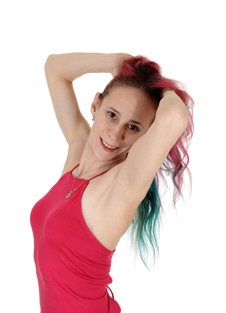 A lovely young woman standing red top with hands in her red hair,
smiling, waist up, isolated for white backgroundの写真素材