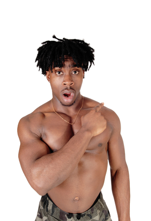 A young shirtless African American man standing in the studio pointingaway with his mouth open for surprise, isolated for white backgroundの写真素材