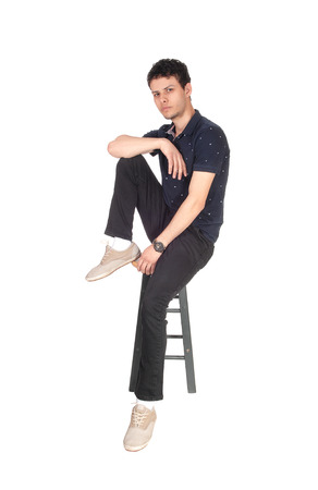 A good looking young man in black clothing sitting on a chair in the
studio, resting, isolated for white backgroundの写真素材