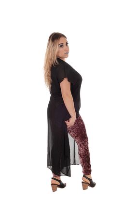 A lovely young woman standing in profile in tights and a
black dress showing her nice figure, isolated for white backgroundの写真素材