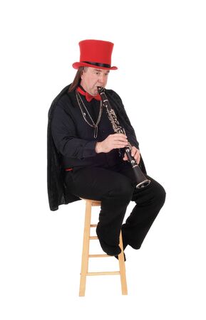 A middle age indigenous man playing his clarinet in a black outfit and
red hat and bow, isolated for white backgroundの写真素材