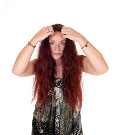 A lovely woman smiling and holding her long messy red hair on the 
side, isolated for white backgroundの写真素材