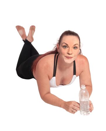 A woman in exercise outfit lying on the floor on her stomach and
holding a water bottle in her hand, isolated for white backgroundの写真素材