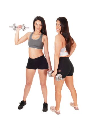 Two pretty women in exercise outfits standing in the studio working
out with there dumbbells, isolated for white backgroundの写真素材