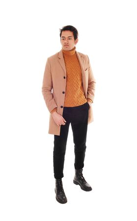 A tall young man standing in a beige coat in the studio
looking away, isolated for white backgroundの写真素材