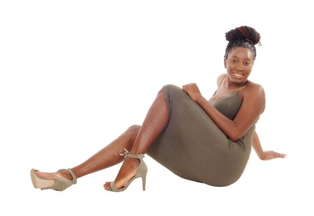 A beautiful African American woman in a dress sitting on
the floor, smiling, isolated for white backgroundの写真素材