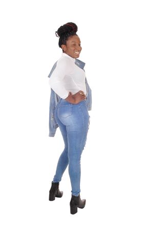 A tall young African American woman standing in jeans, 
from the back, jacket over her shoulder, isolated for white background
の写真素材
