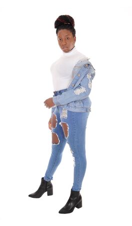 A young African American woman standing in ripped jeans with herjacket over her shoulder and white top, isolated for white backgroundの写真素材