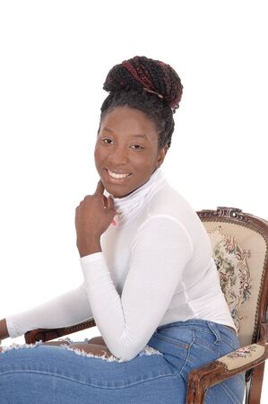 A smiling African woman sitting in a white top and jeans in an
old armchair, looking into the camera, isolated for white background
の写真素材