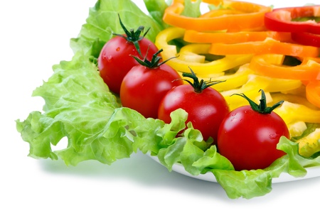 Mix of fresh vegetables from a colored paprika on leaves of green salad on a white backgroundの写真素材