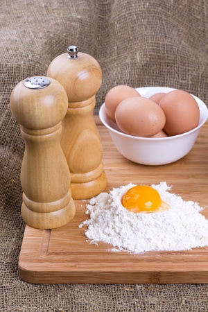 Yolk, eggs of house hens, salt and pepper with wheat flour on kitchen to a boardの写真素材